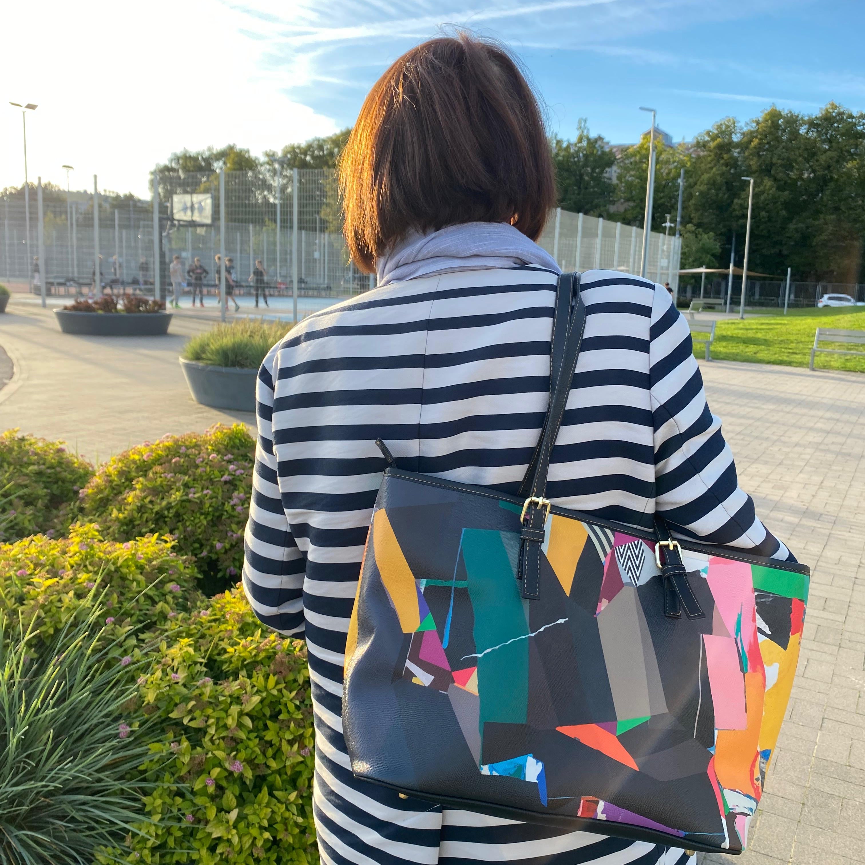 Person wearing a striped outfit with a colorful bag outdoors.