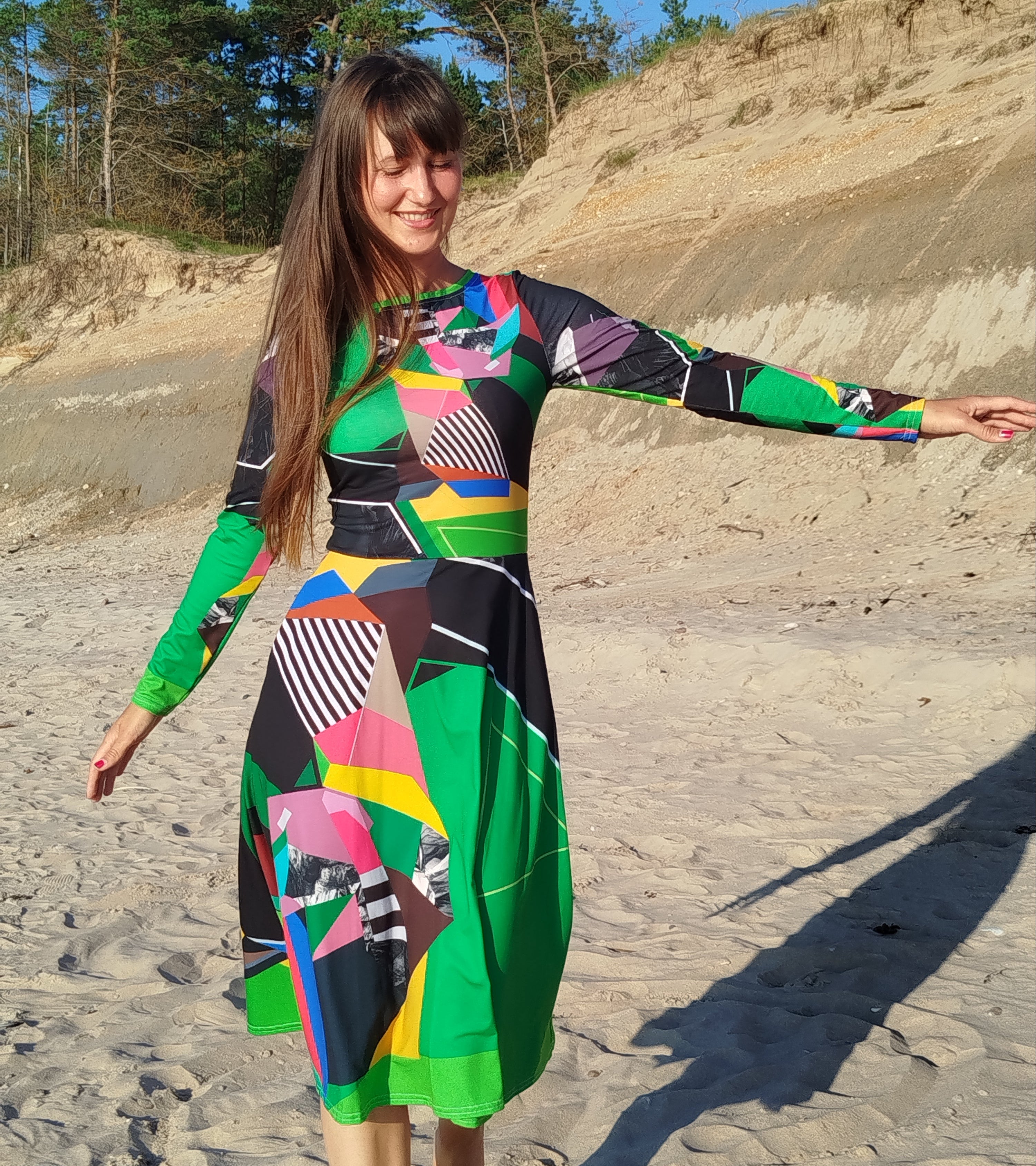Woman modeling a green abstract midi dress with long sleeves and artistic abstract print, elegant feminine silhouette, modern statement midi dress for women